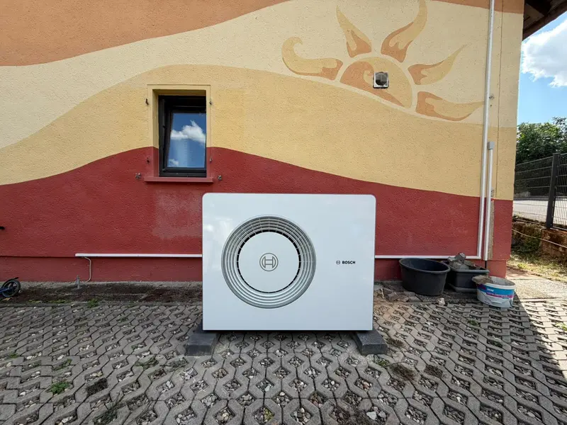 Zunanja enota toplotne črpalke Bosch ob poslikani fasadi